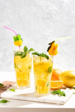 Limonlu limonata ya da mojito kokteyli, limon, portakal ve fesleğen. Mermer kesme tahtasındaki buzlu soğuk içecek ya da içecek.