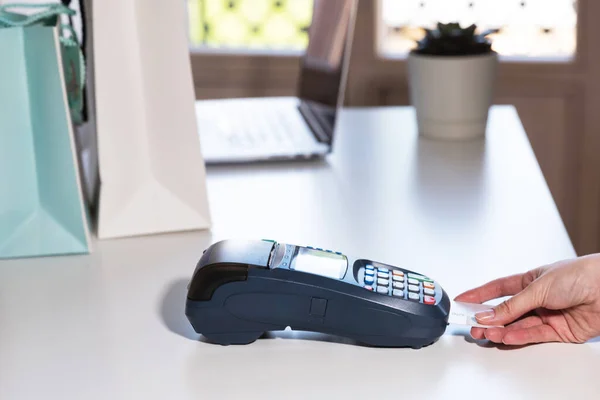 Woman pay by card. NFC payment terminal on a white table. Credit card or phone pay pos banking device, card machine.