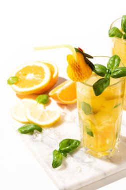 Limonlu limonata ya da mojito kokteyli, limon, portakal ve fesleğen. Mermer kesme tahtasındaki buzlu soğuk içecek ya da içecek.