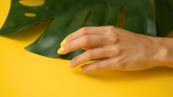 Mano femenina con una hermosa manicura elegante amarilla con arte de uñas — Vídeos de Stock