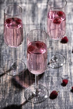 Ahududulu pembe kokteyl. Ahşap masada bir kadeh şampanya.