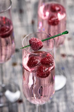 Ahududulu pembe kokteyl. Ahşap masada bir bardak şampanya ve parıldayan yıldızlar.