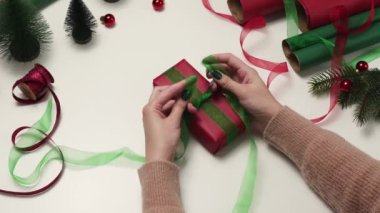 Hediye üzerine yeşil kurdele bağlayan kadın el işi. El işi kırmızı kağıda sarılmış..