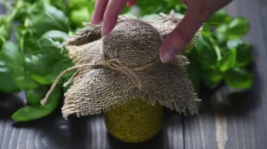 Küçük bir kavanoz ev yapımı pesto sosu ve yeşil taze fesleğen.