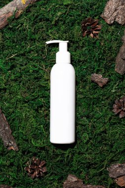 Yeşil yosun arka planında beyaz bir şişede kozmetik ürünü.