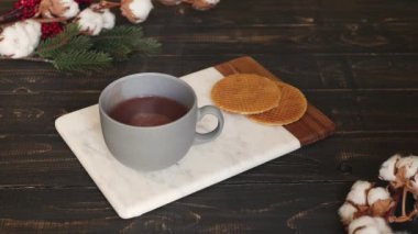 Bir kadın sıcak kakao içeceğiyle krem şanti karıştırıyor. Mermer tahtada ve ahşap masada çikolata içeceği