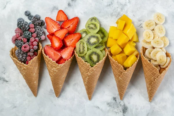 Conceito de dieta saudável - frutas e bagas congeladas em cones de sorvete em fundo rústico — Fotografia de Stock