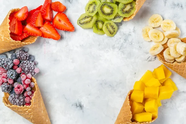 Концепція здорового харчування - фрукти та заморожені ягоди в конусах морозива на сільському фоні — стокове фото