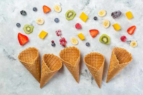 Концепція здорового харчування - фрукти та заморожені ягоди в конусах морозива на сільському фоні — стокове фото