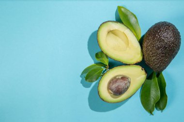 Parlak arka plan üzerinde avokado dilimleri. Bütün ve yarısı yaprakları ile. Tasarım öğesi için ürün etiket