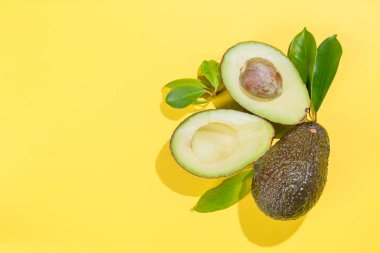Parlak arka plan üzerinde avokado dilimleri. Bütün ve yarısı yaprakları ile. Tasarım öğesi için ürün etiket