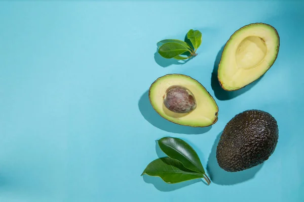 Schijfjes avocado op lichte achtergrond. Geheel en de andere helft met bladeren. Ontwerpelement voor productlabel — Stockfoto