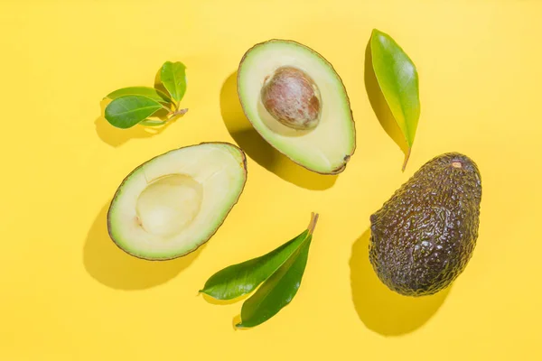 Slices of avocado on bright background. Whole and half with leaves. Design element for product label — Stock Photo, Image