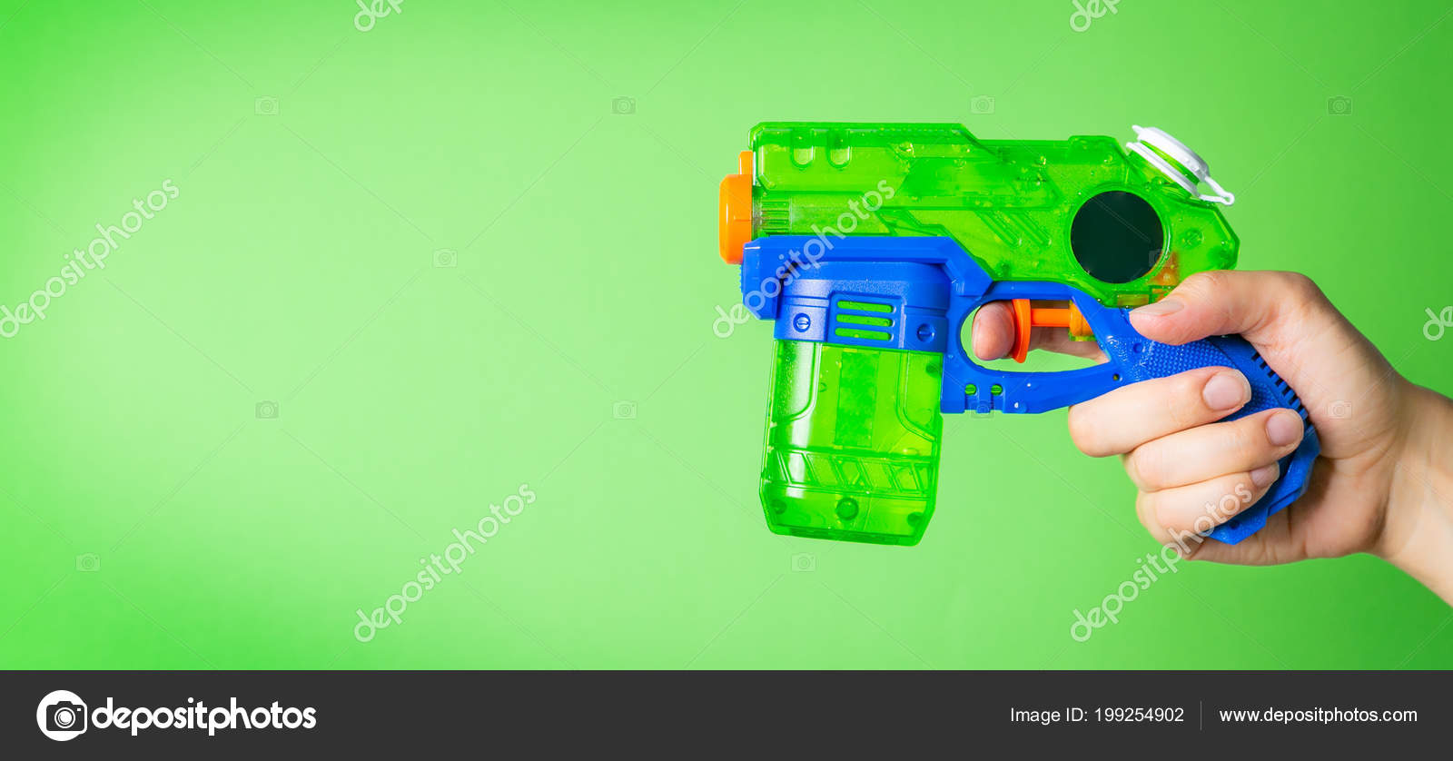 Hand holding water gun in front of bright green background Stock Photo