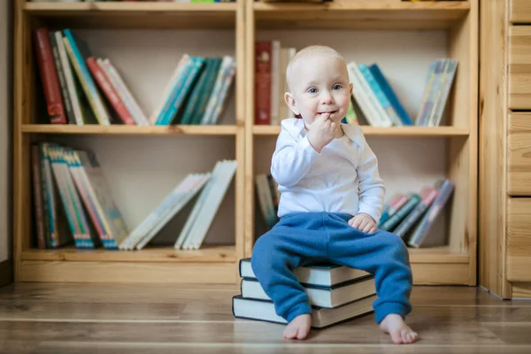 Ragazza del bambino seduta con i libri davanti agli scaffali dei libri — Foto Stock