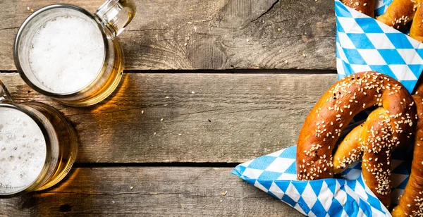 Oktoberfest koncept - pretzels och öl på rustika trä bakgrund — Stockfoto