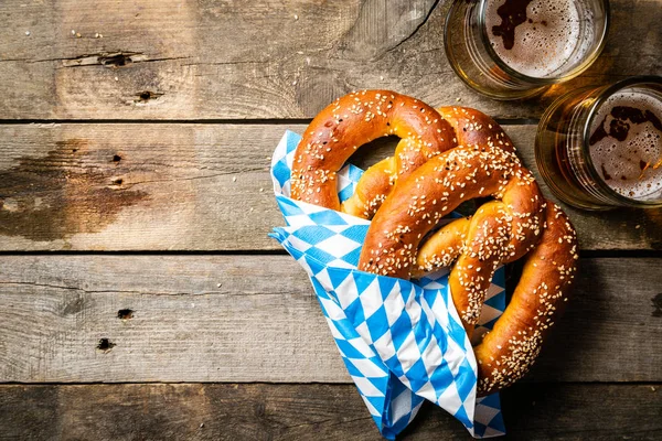 Oktoberfest koncept - pretzels och öl på rustika trä bakgrund — Stockfoto