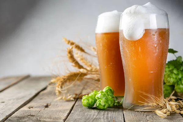 Cerveja e ingredientes lúpulo, trigo, cevada sobre fundo de madeira — Fotografia de Stock