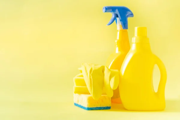 Cleaning supplies - yellow bottles, sprays sponge on bright pastel background — Stock Photo, Image