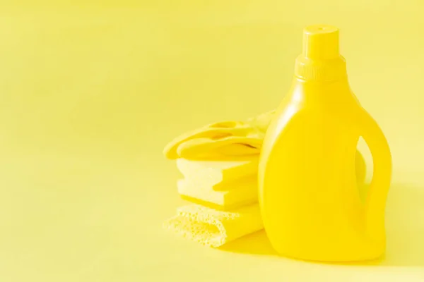 Cleaning supplies - yellow bottles, sprays sponge on bright pastel background — Stock Photo, Image