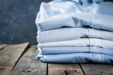 Rustik arka plan üzerinde erkek katlanmış gömlek yığını