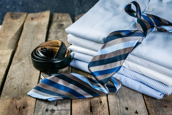 Выбор мужской одежды - пачка сложенных рубашек, галстук, пояс, запонки — стоковое фото
