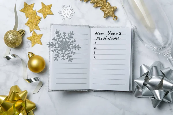 New year resolutions concept - notebook with list of goals and silver gold decorations — Stock Photo, Image