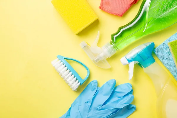 Cleaning concept - cleaning supplies on pastel yellow background
