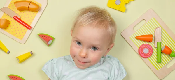 Bebê sorridente com alimentos de brinquedo de madeira de bebê e ingredientes — Fotografia de Stock