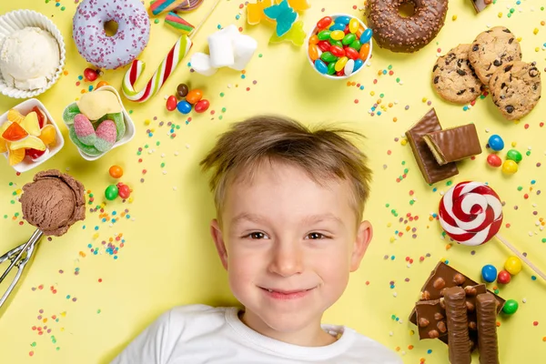 Ragazzo con selezione di dolci su sfondo luminoso — Foto Stock