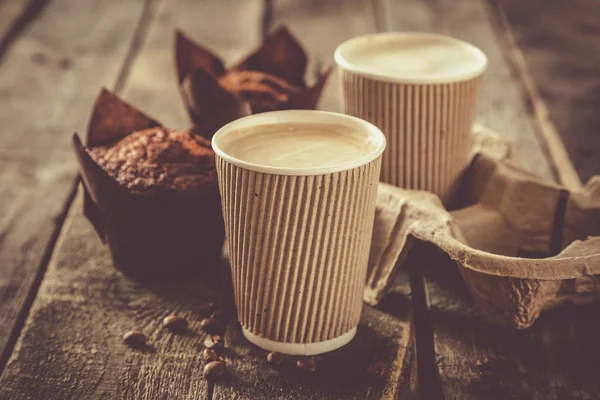 Coffee to go with muffin on wood background