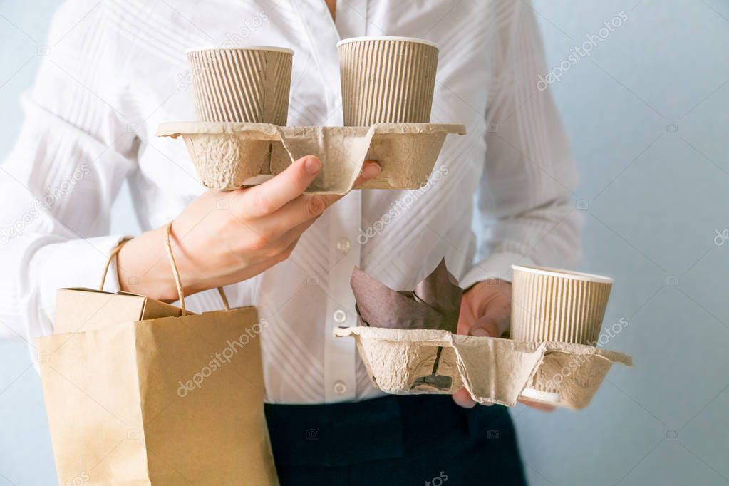 Female holding coffee containers, paper bag withfood containers. Food and coffee delivery