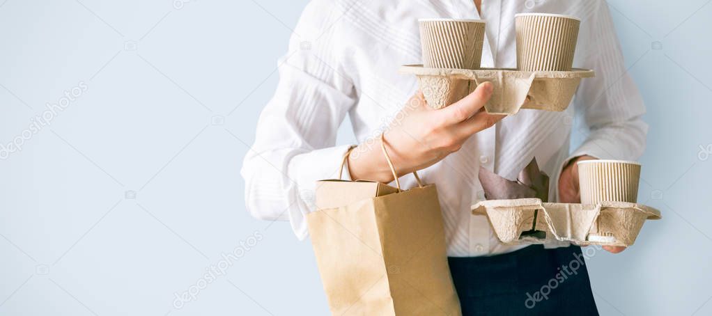 Female holding coffee containers, paper bag withfood containers. Food and coffee delivery