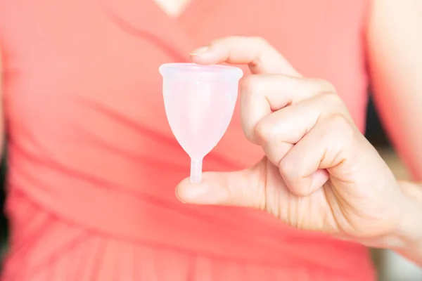 Концепция нулевых отходов - женщина держит менструальную чашку в розовом платье — стоковое фото