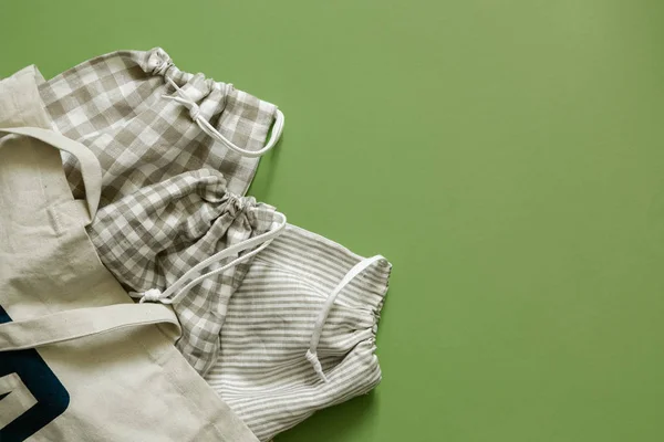 Zero waste concept - reusable cotton bags and glass jars on green background — 스톡 사진