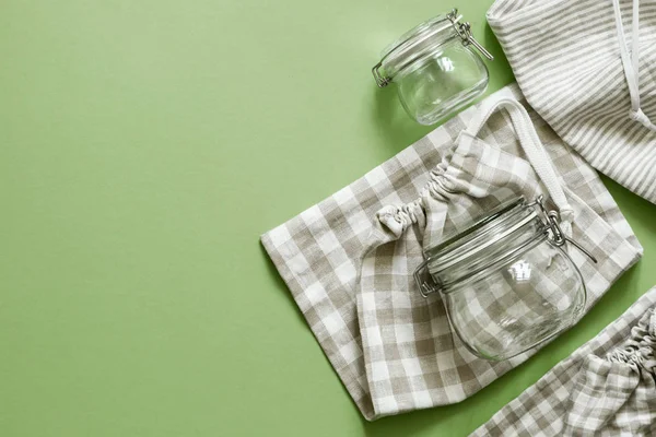 Sıfır atık kavramı - yeniden kullanılabilir pamuk torbaları ve yeşil arka planda cam kavanozlar — Stok fotoğraf