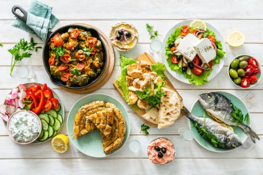 Geleneksel Yunan yemekleri seçimi - salata, meze, pasta, balık, tzatziki, ahşap arka plan üzerinde dolma