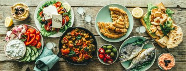 Geleneksel Yunan yemekleri seçimi - salata, meze, pasta, balık, tzatziki, ahşap arka plan üzerinde dolma