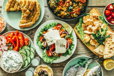 Geleneksel Yunan yemekleri seçimi - salata, meze, pasta, balık, tzatziki, ahşap arka plan üzerinde dolma