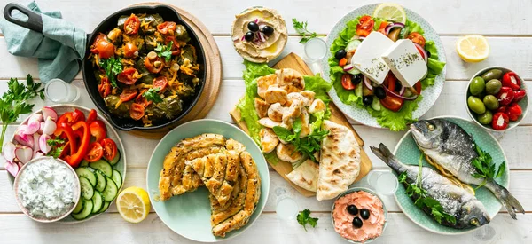 Selección de comida griega tradicional - ensalada, meze, pastel, pescado, tzatziki, dolma sobre fondo de madera —  Fotos de Stock