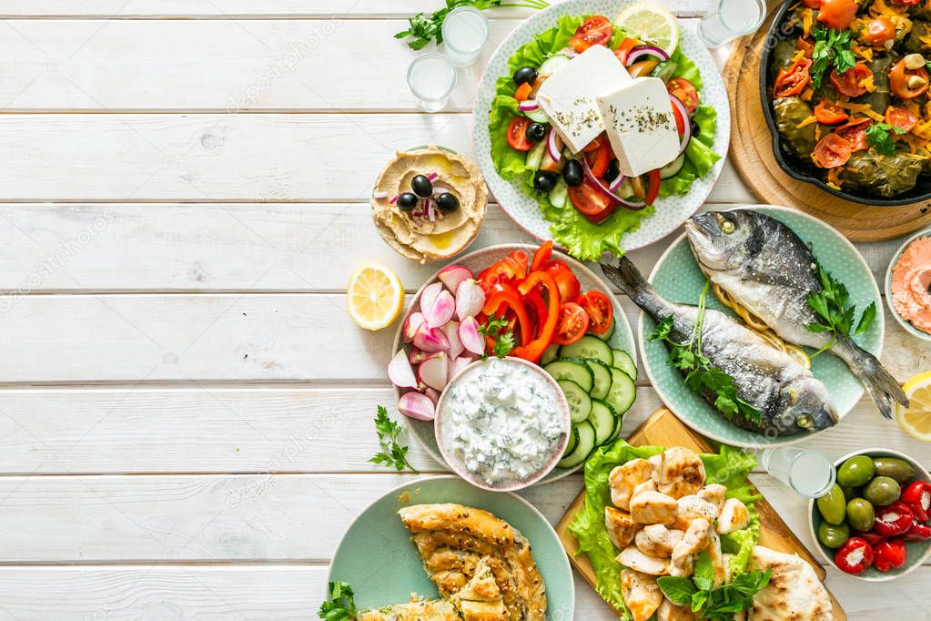 Selection of traditional greek food - salad, meze, pie, fish, tzatziki, dolma on wood background