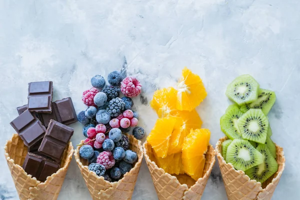 Hälsosam kost koncept - frukter och frysta bär i glass kottar på rustika bakgrund — Stockfoto