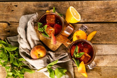 Buzlu çay ve bardaktaki malzemeler ahşap arka planda.