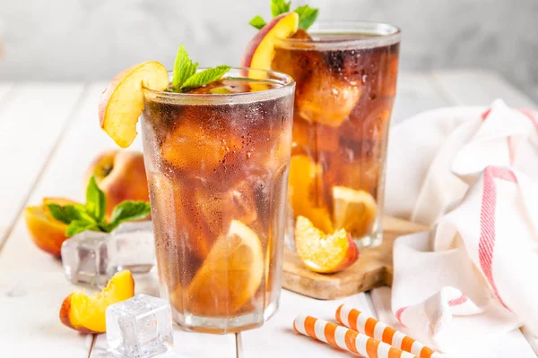 Iced tea and ingredients in glasses on wood background