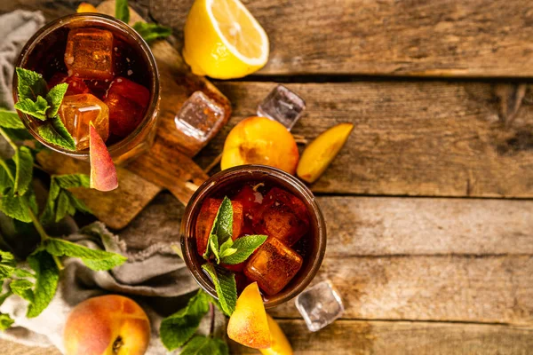 Iced tea and ingredients in glasses on wood background