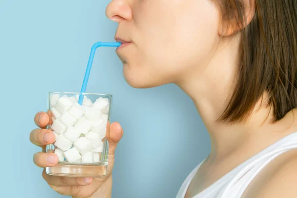 Excessive sugar consumption concept - female drinking from glass with sugar cubes — Stock Photo, Image