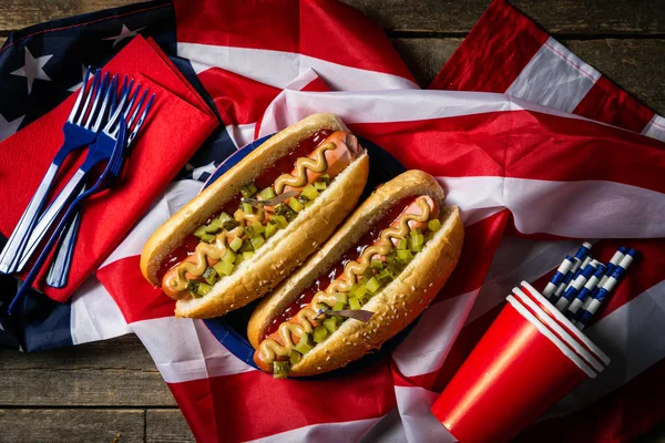 Día Nacional del Trabajo, Día de los Caídos, Día de la Bandera, 4 de julio - perros calientes con salsa de tomate y mostaza sobre fondo de madera —  Fotos de Stock