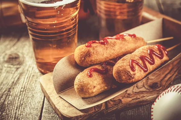 Corn dogs and beer on rustic background