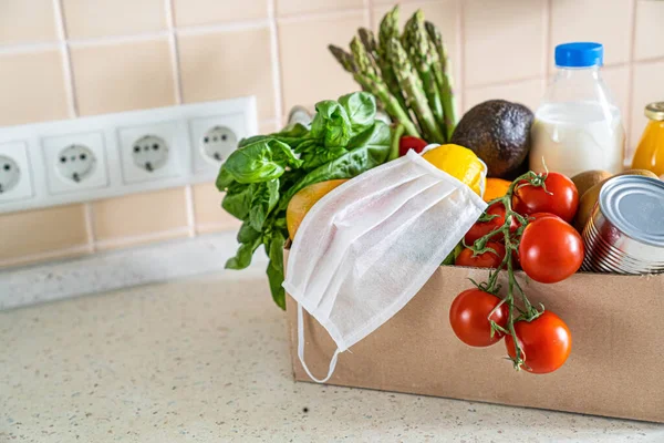Safe food delivery concept - groceries in box with medical mask