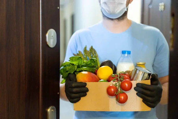 Safe food delivery concept - delivery man holds gloceries